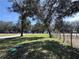 Landscaped yard with mature trees lining the street, offering a peaceful setting at 9285 Se Highway 42, Summerfield, FL 34491