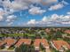 Picturesque aerial view featuring homes with red tile roofs nestled around a scenic lake with a fountain at 5162 Harbour Dr, Oxford, FL 34484