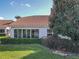 Rear exterior view of home with large windows, lush landscaping, and a Spanish tile roof at 5162 Harbour Dr, Oxford, FL 34484