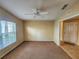 Neutral-toned bedroom features plush carpet, window with blinds, and a ceiling fan at 5162 Harbour Dr, Oxford, FL 34484