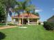 A view of the yellow community clubhouse featuring well-maintained landscaping and tall palm trees at 5162 Harbour Dr, Oxford, FL 34484