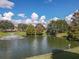 Picturesque pond featuring a fountain, surrounded by mature trees and manicured lawn at 5162 Harbour Dr, Oxford, FL 34484