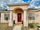 Inviting home entrance with a red door, decorative wreath, and column-supported porch at 8335 Se 162Nd Pl, Summerfield, FL 34491
