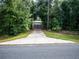 Long driveway leading to a storage building surrounded by lush, mature trees at 12805 Sw 64Th Ln, Ocala, FL 34481