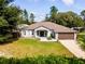 Charming single-story home featuring a manicured lawn, lush landscaping, and attached two-car garage at 12805 Sw 64Th Ln, Ocala, FL 34481