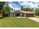 Charming single-story home featuring a manicured lawn, lush landscaping, and attached two-car garage at 12805 Sw 64Th Ln, Ocala, FL 34481