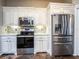 Updated kitchen features stainless steel appliances, sleek white cabinetry, and a tile backsplash at 12805 Sw 64Th Ln, Ocala, FL 34481
