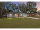 Exterior home featuring a well-manicured lawn, gray roof, and inviting curb appeal at dusk at 15282 Sw 27 Ln, Ocala, FL 34481