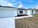 The front exterior of the house with a bright white door, a large driveway, and nicely trimmed landscaping at 37 Guava Terrace Radl, Ocklawaha, FL 32179