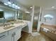 Bright bathroom with a double sink vanity, a glass-enclosed shower, and a separate soaking tub at 10923 Sw 38Th Ave, Ocala, FL 34476