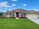 Beautiful single-story home featuring a red double-door entrance, well-kept lawn, and a two-car garage at 10923 Sw 38Th Ave, Ocala, FL 34476