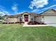 Beautiful home with a well-manicured lawn, red front door, and elegant landscaping at 10923 Sw 38Th Ave, Ocala, FL 34476