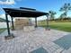 Outdoor kitchen area features a stone grill, dark covered roof, and brick paver flooring at 10923 Sw 38Th Ave, Ocala, FL 34476
