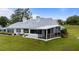 Wide backyard view of a home with manicured lawn, back patios, and mature trees at 6042 Topsail Rd, Lady Lake, FL 32159