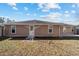 Back of home featuring neutral siding, functional door, and adjacent yard at 33 Pecan Pass Run, Ocala, FL 34472