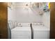 Laundry room with a white washer and dryer; also includes shelving for storing laundry supplies at 33 Pecan Pass Run, Ocala, FL 34472