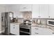 Modern kitchen featuring stainless refrigerator, white cabinets and backsplash, and stainless double oven at 4535 Se 32Nd Pl, Ocala, FL 34480