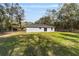 Spacious backyard with lush lawn, mature trees, and a modern single-story house at 15504 Sw 29 St, Ocala, FL 34481