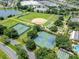 This aerial shows tennis and baseball courts along with well manicured lawns and a pond at 17789 Se 113Th Ter, Summerfield, FL 34491