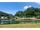 Picturesque Stonecrest community pond view with lush trees, plants, and manicured landscaping under a clear sky at 17789 Se 113Th Ter, Summerfield, FL 34491
