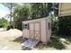 Tan outdoor shed with light green trim, double doors, and a wooden ramp at 727 Ne 130Th Ter, Silver Springs, FL 34488