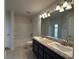 Bathroom with double sinks, granite countertop, tub with shower, tile flooring, and modern lighting at 9115 Sw 49Th Ct, Ocala, FL 34476