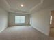 Spacious primary bedroom with a tray ceiling, neutral walls, and a large window at 9115 Sw 49Th Ct, Ocala, FL 34476