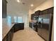 Spacious kitchen with dark cabinets, stainless steel appliances, granite countertops, and tile flooring at 9115 Sw 49Th Ct, Ocala, FL 34476