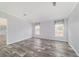 Open living room with gray walls and light gray wood floor, natural light from two windows at 11837 Se 165 Ave, Ocklawaha, FL 32179