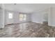 Bright living room features wood-look flooring, a window with blinds, and an entry door at 11837 Se 165 Ave, Ocklawaha, FL 32179