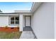 Close-up view of the front door with gray trim, fresh landscaping, and a freshly painted, modern exterior at 13848 Sw 102 St, Dunnellon, FL 34432