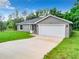 Charming single-story home features a gray exterior, a spacious two-car garage, and a long driveway at 24780 Nw Hillsdale Ave, Dunnellon, FL 34431