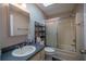 Cozy bathroom featuring a shower-tub combo with sliding glass doors and vanity with decorative shelving at 10817 Se 51St Ave, Belleview, FL 34420