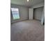Bedroom with neutral walls, carpet, a closet, and a window overlooking the yard at 11610 Sw 59Th Terrace, Ocala, FL 34476