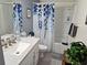 Bright bathroom showcasing a white vanity with a white countertop and a shower with a blue leaf curtain at 19370 Saint Benedict Dr, Dunnellon, FL 34432