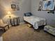 Cozy bedroom featuring a twin bed with a blue quilt and a classic lamp on a glass table at 19370 Saint Benedict Dr, Dunnellon, FL 34432