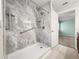 Modern walk-in shower featuring marble-look tile, grab bars, and updated fixtures at 4219 Ne 33Rd Ave, Ocala, FL 34479