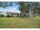 Well maintained backyard with mature trees, lush green grass and a home with tan siding at 8150 Sw 108Th St, Ocala, FL 34481