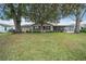 Lush backyard featuring green grass, mature trees, and a charming house at 8150 Sw 108Th St, Ocala, FL 34481
