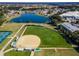 Aerial view of a well-maintained baseball field with a lake and homes in the background at 10927 Se 168Th Loop, Summerfield, FL 34491
