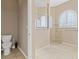 Bathroom showcasing a toilet and glass enclosed tiled walk-in shower with a view to the arch window at 10927 Se 168Th Loop, Summerfield, FL 34491