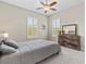 Bright bedroom features a ceiling fan, plantation shutters and wooden dresser at 10927 Se 168Th Loop, Summerfield, FL 34491