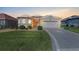 Charming single-story home with manicured lawn, arched windows and a two-car garage at sunset at 10927 Se 168Th Loop, Summerfield, FL 34491
