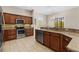 Well-lit kitchen boasts stainless steel appliances, tile floors, wood cabinetry, and stone countertops at 10927 Se 168Th Loop, Summerfield, FL 34491