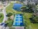Aerial view of multiple, well-maintained pickleball courts near a pond in a residential community at 10927 Se 168Th Loop, Summerfield, FL 34491