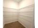 Walk-in closet features built-in metal shelving and wood-look tile flooring at 14711 Sw 69Th Court Rd, Ocala, FL 34473