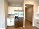 Kitchen view showcasing stainless steel refrigerator, ample white cabinetry, quartz countertops, and adjacent laundry room access at 2647 Sw 154Th Ln, Ocala, FL 34473