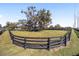 Large round pen with black rail fencing and a mature oak tree at 10555 W Highway 40, Ocala, FL 34482