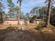 Exterior view of the house and garage with a backdrop of tall trees, offering a sense of privacy and tranquility at 14830 Se 61St Street Rd, Ocklawaha, FL 32179