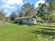 Exterior view of the home on a well-maintained lawn with mature trees and blue skies at 2605 Ne 14Th Ave, Ocala, FL 34470
